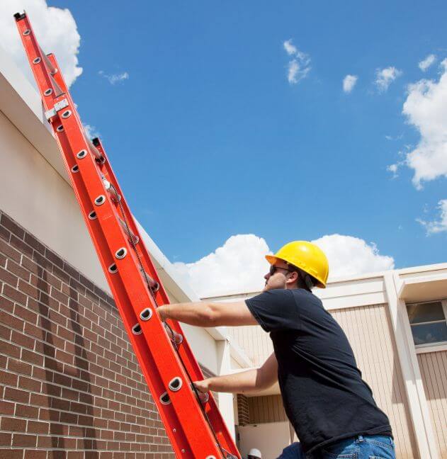 Roofer climbing roof of a commercial building